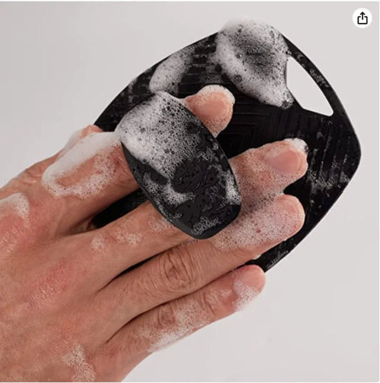brosse exfoliante poignee dans une main mousseuse