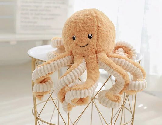 peluche pieuvre brun sur table blanche