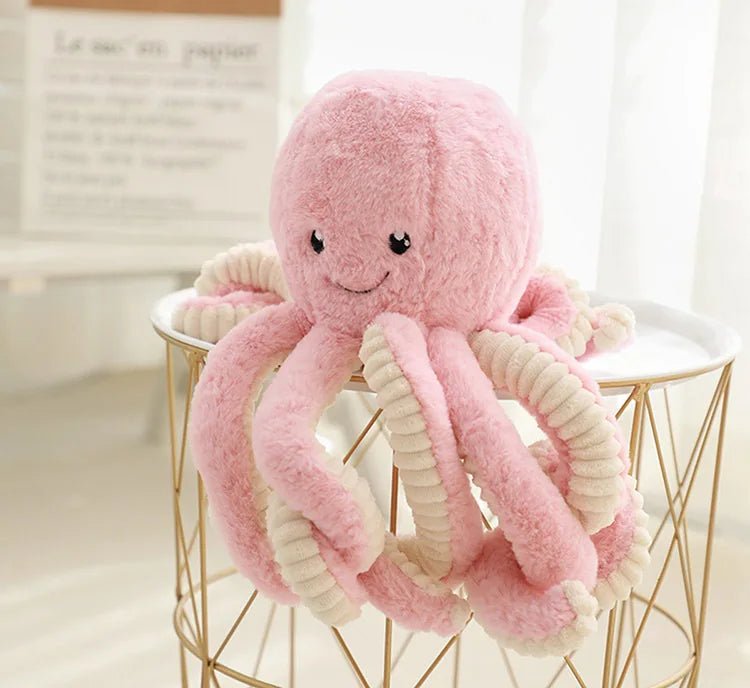 peluche pieuvre rose sur table blanche
